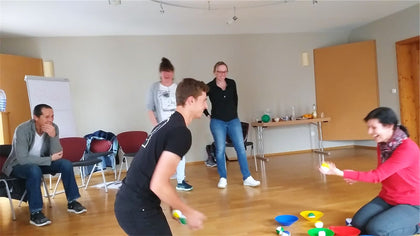 A woman laughing as she catches a ball, others watching