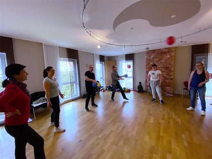 A group of adults of all ages in a training room, one throwing a ball