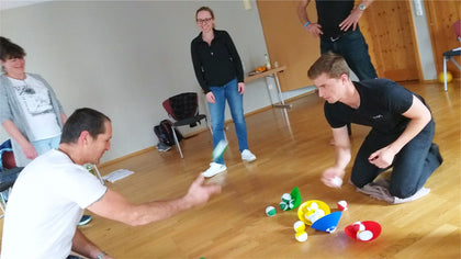 Adults with balls and coloured discs on the floor, one kneeling